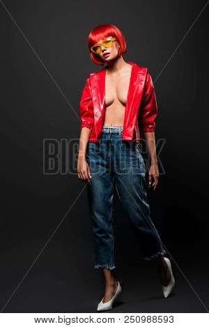 Attractive Young Woman In Short Red Raincoat On Bare Skin On Grey