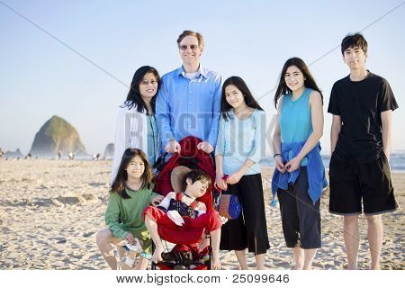 Grande famiglia di sette in piedi sulla spiaggia con l'oceano