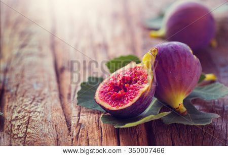 Ripe fig fruits with leaf close-up. Beautiful sweet fresh organic figs on a wooden table. Border label design. Healthy vegan food