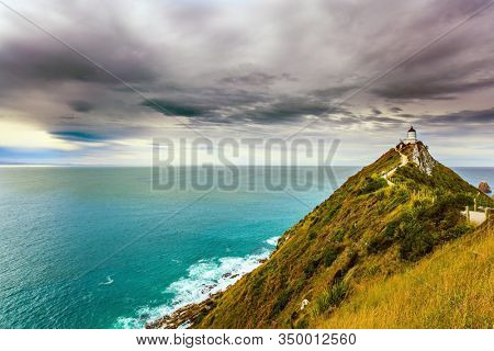 The picturesque coast of the Pacific Ocean. Nugget Point Lighthouse on the Cape Nugget. South Island, New Zealand. The concept of active, environmental and photo tourism