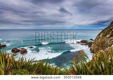  South Island, New Zealand. The picturesque coast of the Pacific Ocean near Cape Nugget. Sunset portends a storm. The concept of active, environmental and photo tourism