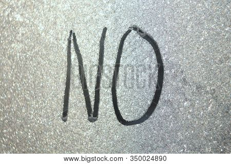 The Inscription On Frozen Window Pane. Word No Written On Blurry Translucent Background. Stock Photo
