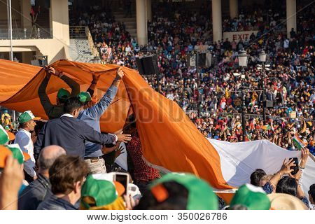 Amritsar, India - Febuary 8, 2020: Crowds In The Stadium Seating Pass Up And Hold An Indian Flag In 