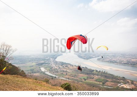Paragliding In The Sky. Paraglider  Flying Over Landscape From Beautiful View Mekong River At Wat Ph