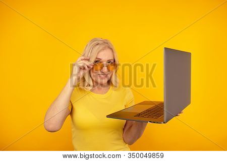 Portrait Of Happy Exited Abult Lady With Laptop Isolated Over The Yellow Studio.