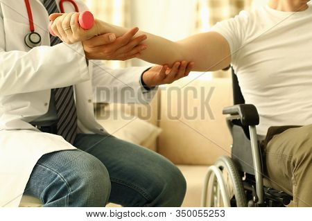 Male Doctor Helps Lift Dumbbell To Disabled Patient Rehabilitation Therapy Concept. Process Of Recov