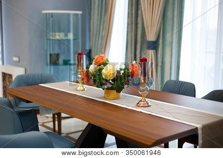 Large dining table with a tablecloth and two candles. In the middle of the table is a gorgeous bouquet of flowers.