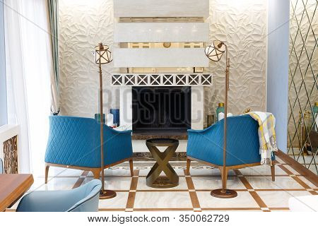 An organized resting place for the owner of the house and his wife by the fireplace. A cozy corner with two blue armchairs and a set of candles to give the atmosphere a special romanticism.