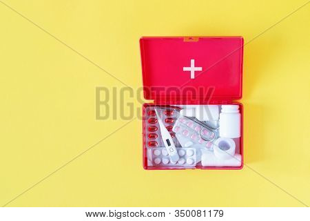 First Aid Kit Red Box With Medical Equipment And Medications For Emergency Top View On Pastel Yellow