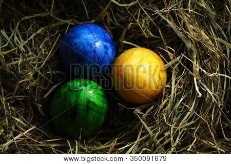 Three Colored Easter Eggs In Hay In The Eastertime