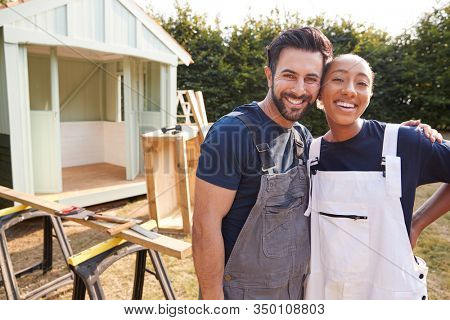 Portrait Of Couple Taking A Break From Building Outdoor Summerhouse In Garden