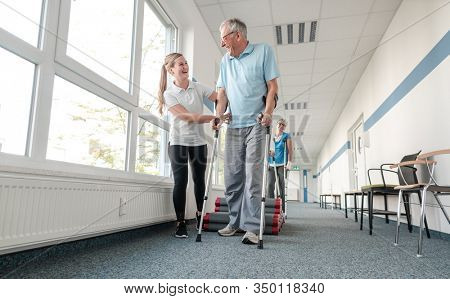 Seniors in rehabilitation learning how to walk with crutches after having had an injury