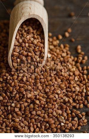 Scoop And Buckwheat Macro View On Rustic Background. Close Up Raw Buckwheat Background.