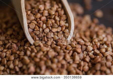 Scoop And Buckwheat Macro View On Rustic Background. Close Up Raw Buckwheat Background.