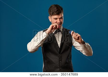 Noob In Poker, In Black Vest And White Shirt. Holding Some Colored Chips. Posing Against Blue Backgr