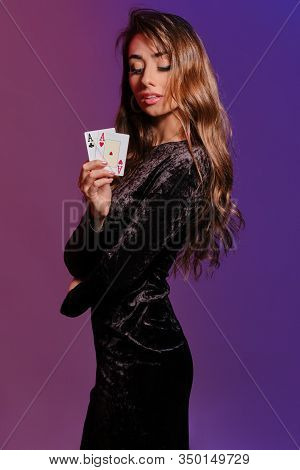 Brunette Girl In Black Velvet Dress Showing Two Playing Cards, Posing Sideways On Coloful Background