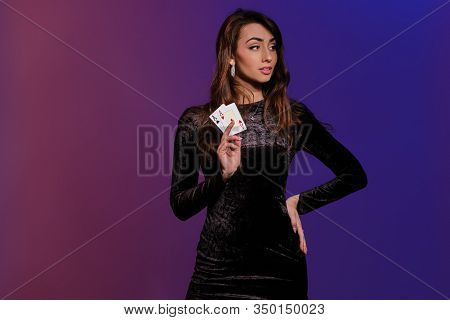 Brunette Woman In Black Velvet Dress Showing Two Playing Cards, Posing Against Coloful Background. G