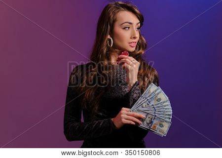 Brunette Girl In Black Velvet Dress Showing Two Red Chips And Some Cash, Posing Against Coloful Back