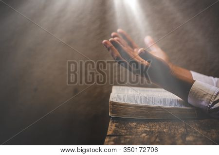 Hands Folded In Prayer On A Holy Bible In Church Concept For Faith