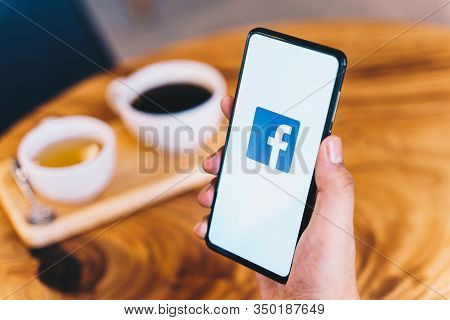 Chiang Mai, Thailand - Jan.18,2020: Man Holding Xiaomi Mi Mix3 With Facebook App On Wooden Table At 
