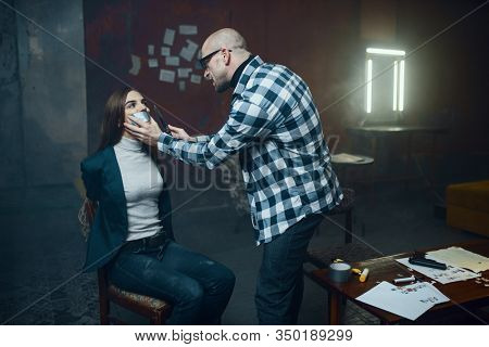 Maniac kidnapper taping his victim's mouth shut