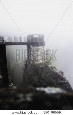 Tiny Tower Connected To The Basteibruecke With A Wooden Bridge In The Fog At Basteigebiet In Saxony,