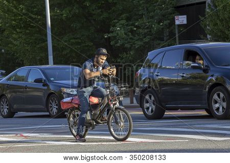 Bronx, New York/usa - August 10, 2019: Hispanic Man Looks At Cel While Sitting On Bike And Waiting F