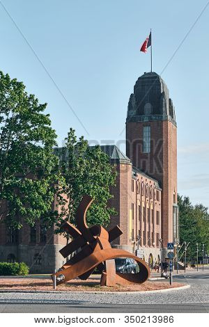 Joensuu. Finland - July 20, 2019: On The Foreground Brand New Art Object On The Center Of Roundabout