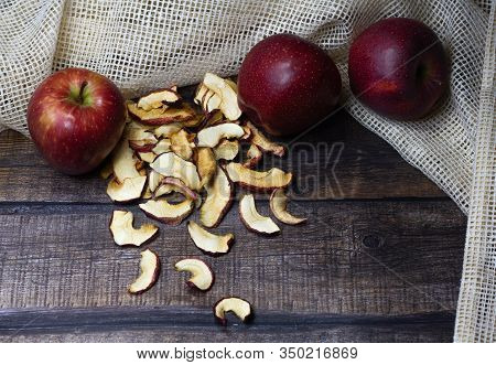 Dried Apple Chips And Three Red Apples On A Brown Wooden Table. Organic Natural Food. Close Up. Top 