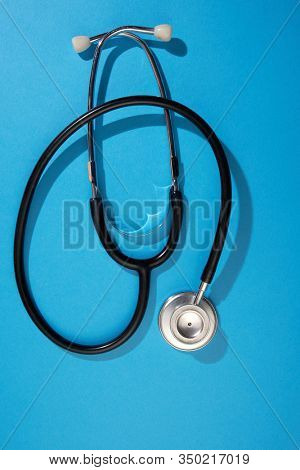 black stethoscope on a blue background top view with copy space.