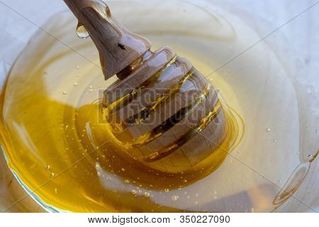 Honey Dipper On The Bee Honeycomb Background. Honey Tidbit In Glass Jar And Honeycombs Wax