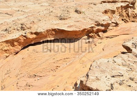 Background Of Yellow Sand With Small Stones After Rain. Soil Erosion After Heavy Rainfall And Precip
