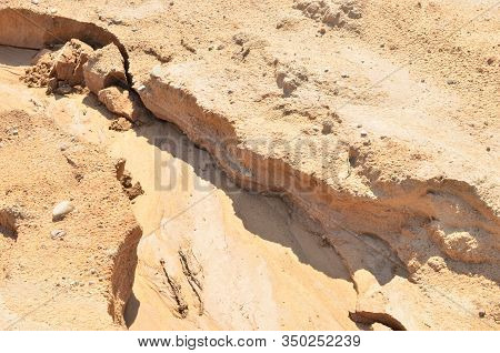 Background Of Yellow Sand With Small Stones After Rain. Soil Erosion After Heavy Rainfall And Precip