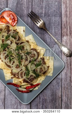 Beshbarmak Is A National Kyrgyz Dish - Square Pasta With Boiled Meat And Onions. On Wooden Backgroun