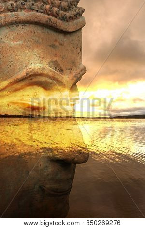 Figure Of A Buddha With A Lake At Sunrise In The Background