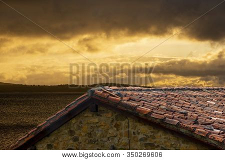The Roof Of An Old House On The Lake At Sunrise