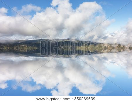 A Lake In The Mountains With Clouds Reflections