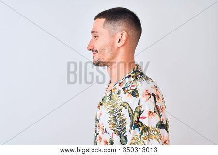 Young handsome man wearing Hawaiian summer shirt over isolated background looking to side, relax profile pose with natural face with confident smile.