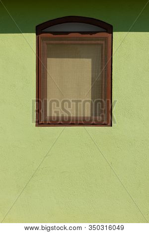 Curtained Brown Window On A Green Textured Wall With A Mosquito Net In The Sunlight..