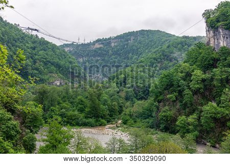 A Gorge In The Mountains With A Suspension Bridge Over It. Skybridge Suspension Bridge Over A Precip