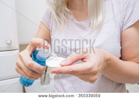 Woman Wetting A Cotton Pad With A Micellar Make Up Remover, Cleansing And Purifying Face Skin.