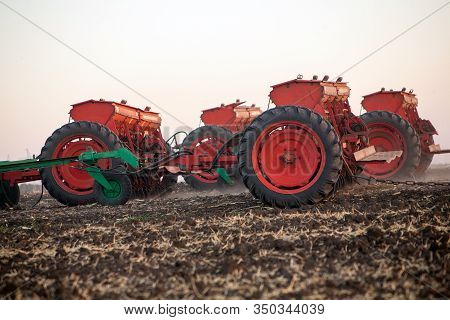 Agricultural Mechanical Seeders Of Grain Crops. Tactor With A Seeder Sows Grain In The Field. A Farm