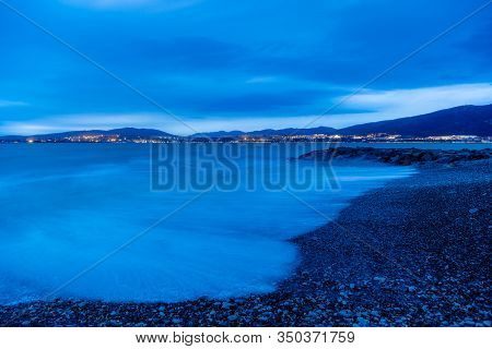 Gelendzhik Beach In The Evening In A Storm. The Waves At High Speed Turn Into A Blue Fog. Pebble Bea