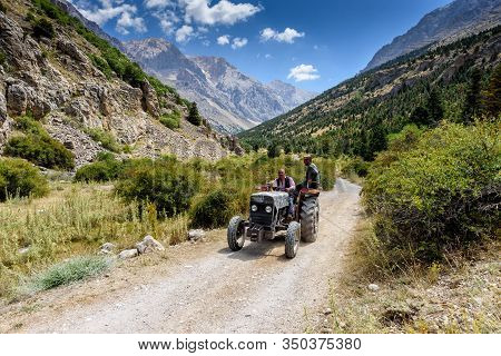 Turkey, Chamard - August 3, 2019: An Elderly Turkish Man Drives An Old Tractor With A Passenger On A