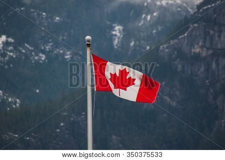 A Picture Of Canada Flag Waving Against The Mountain Lightly Dusted With Snow.   Squamish Bc Canada