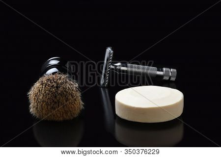 Shaving still life. A razor shaving brush and bar of soap on black.