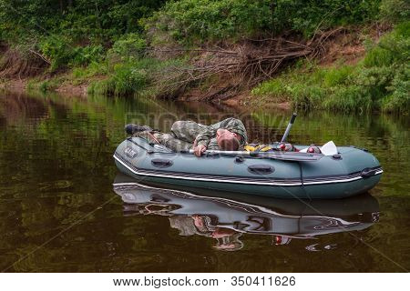 Tuzha, Russia - June 12, 2019: Fisherman Sleeps In A Boat On A River Near The Shore. Pizhma River