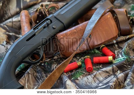 Close-up View Of Black Shotgun Old Leather Cartridge Belt And Red Shotgun Shells On The Camouflage B