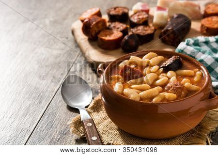 Typical Spanish Fabada Asturiana In Crockpot On Wooden Table. Copy Space
