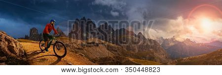 Man cycling on electric bike, rides mountain trail. Man riding on bike in Dolomites mountains landscape. Cycling e-mtb enduro trail track. Outdoor sport activity.